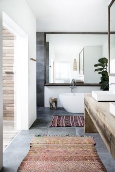 a bathroom with a sink, mirror and rug on the floor in front of it