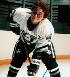 a young man is posing for a photo while holding a hockey stick and wearing glasses