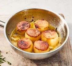 some food is cooking in a pan on a wooden cutting board next to a spoon