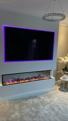 a living room with a large television mounted on the wall and a fire place in front of it