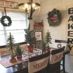 a dining room table with christmas decorations on it and wreaths hanging from the ceiling