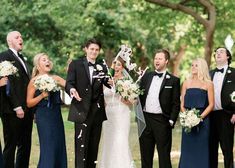 a group of people standing next to each other in front of trees and confetti