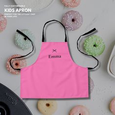 a pink apron with the word emma on it next to doughnuts and donuts