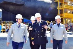 three men in hard hats standing next to an airplane