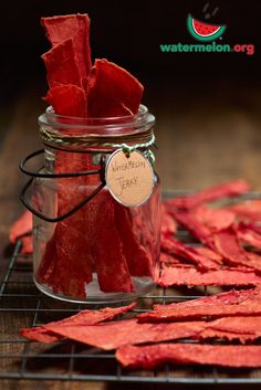 a glass jar filled with red tissue sitting on top of a wooden table next to a wire rack