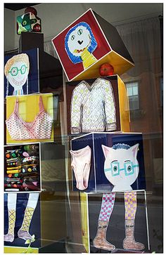 an assortment of paper dolls displayed in a window