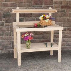 a wooden table with flowers on it in front of a brick wall and stone floor