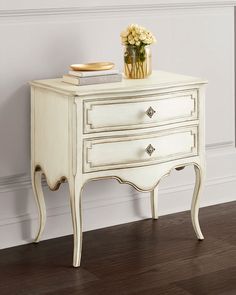 a white dresser with flowers on top and a plate sitting on it's side