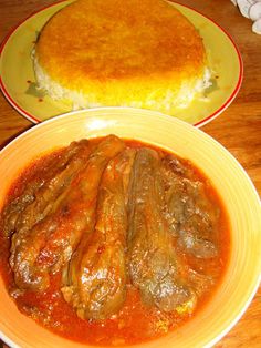 two plates with food on them, one has meat and the other has bread in it