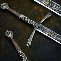 two swords with intricate designs on them sitting next to each other