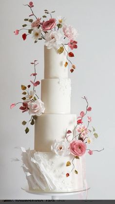 a three tiered white wedding cake with pink and white flowers on the top layer