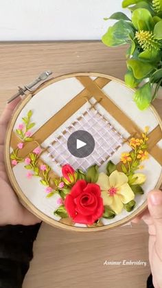 a person is holding a embroidery kit with flowers on it and the video below shows how to make a flower arrangement