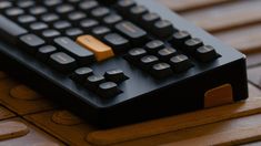 a black and gold computer keyboard sitting on top of a wooden table