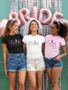 three girls wearing matching shirts and denim shorts standing in front of a backdrop with balloons