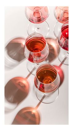 several wine glasses filled with different colored wines