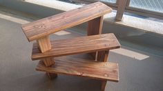 three wooden benches sitting next to each other on the floor in front of a window