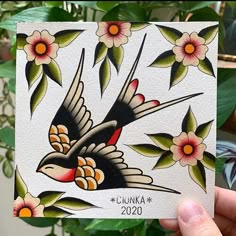 a hand holding up a card with a bird on it and flowers in the background