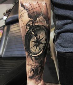 a man's arm with a compass and map tattoo on the left calf sleeve