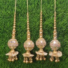 four gold beaded tassels hanging on green grass