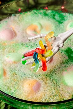 a plastic toothbrush holder in the shape of a human hand with colored gummy bears on it