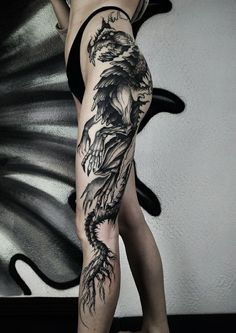 a woman's leg with tattoos on it, and a dragon in the background