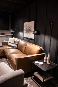 a brown leather couch sitting in a living room next to a table with two lamps on it