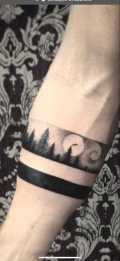 a person with a black and white tattoo on their arm that has mountains in the background