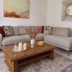 a living room with couches, coffee table and vases on the coffee table