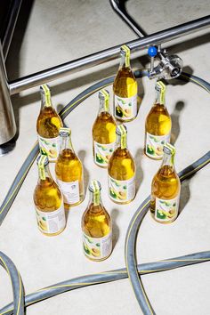 seven bottles of beer are lined up on the floor next to a water faucet