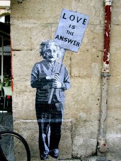 a black and white photo of a man holding a sign that says love is the answer