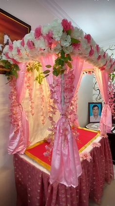 a bed with pink and white flowers on the headboard, draped in pink fabric