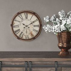 a clock on the wall next to a vase with flowers in it and an old - fashioned dresser