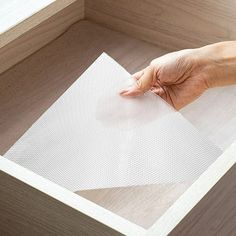 a person's hand on top of a piece of paper in a wooden box