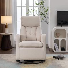 a living room with a white chair and a television on top of a stand in front of a window