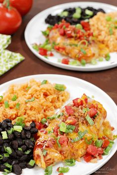 two white plates topped with mexican food and rice next to tomatoes, black beans, and green onions