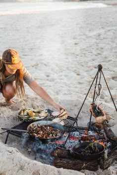 a woman is cooking food on the beach