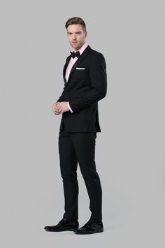 a man in a tuxedo is posing for the camera with his hands on his hips