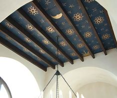 a chandelier hanging from the ceiling in a room with white walls and wooden beams