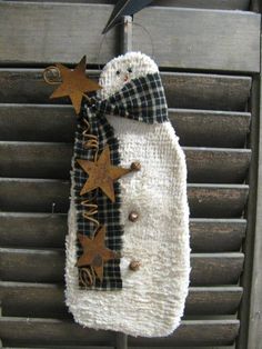 a snowman decoration hanging from the side of a wooden fence with stars on it