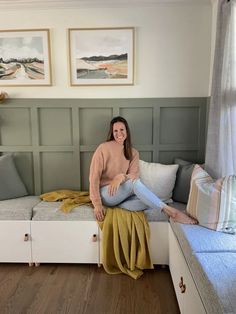 a woman sitting on top of a couch in a living room next to a window