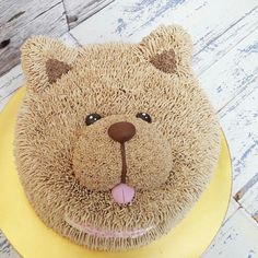 a teddy bear cake sitting on top of a yellow plate next to a wooden table