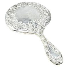 a silver spoon with an ornate design on the top and bottom, sitting in front of a white background