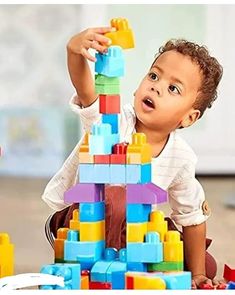 a young boy playing with a large stack of legos on the floor in front of him