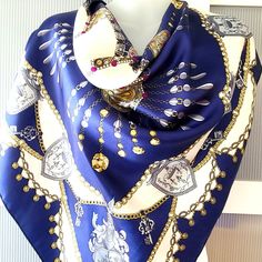 This is a very stylish scarf that features an equestrian theme with various symbols of royalty including chains, jewelry, precious stones and family crest coats of arms that look like shields. The scarf is designed in rich purpolish navy blue, pink and yellow gold colors mixed with cream white. The scarf will add lots of style to your outfit. The scarf is large and can be used as a head scarf. It measures 34x34 inches. No tag is attached to the scarf, but I think it is polyester and it is in exc Elegant Handmade Blue Scarves, Handmade Blue Scarf As A Gift, Handmade Blue Scarves As Gifts, Royal Symbols, Rosa Gold, Satin Scarf, Stylish Scarves, Coat Of Arm, Gold Colors