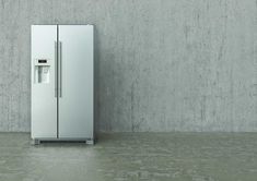 a white refrigerator freezer sitting in front of a cement wall with no one on it