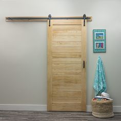 a wooden door sitting next to a laundry basket on top of a hard wood floor