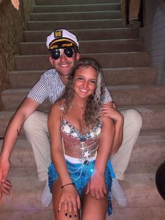 a man and woman sitting on the steps in front of some stairs with their arms around each other