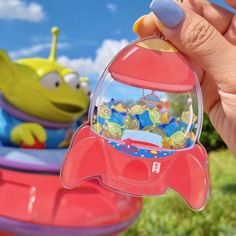 a hand holding a toy in front of a cartoon character on the back of a boat