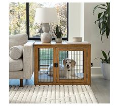 a dog is sitting in its cage on the floor next to a couch and table