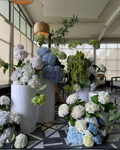 several white vases with blue and green flowers in them sitting on a checkered floor